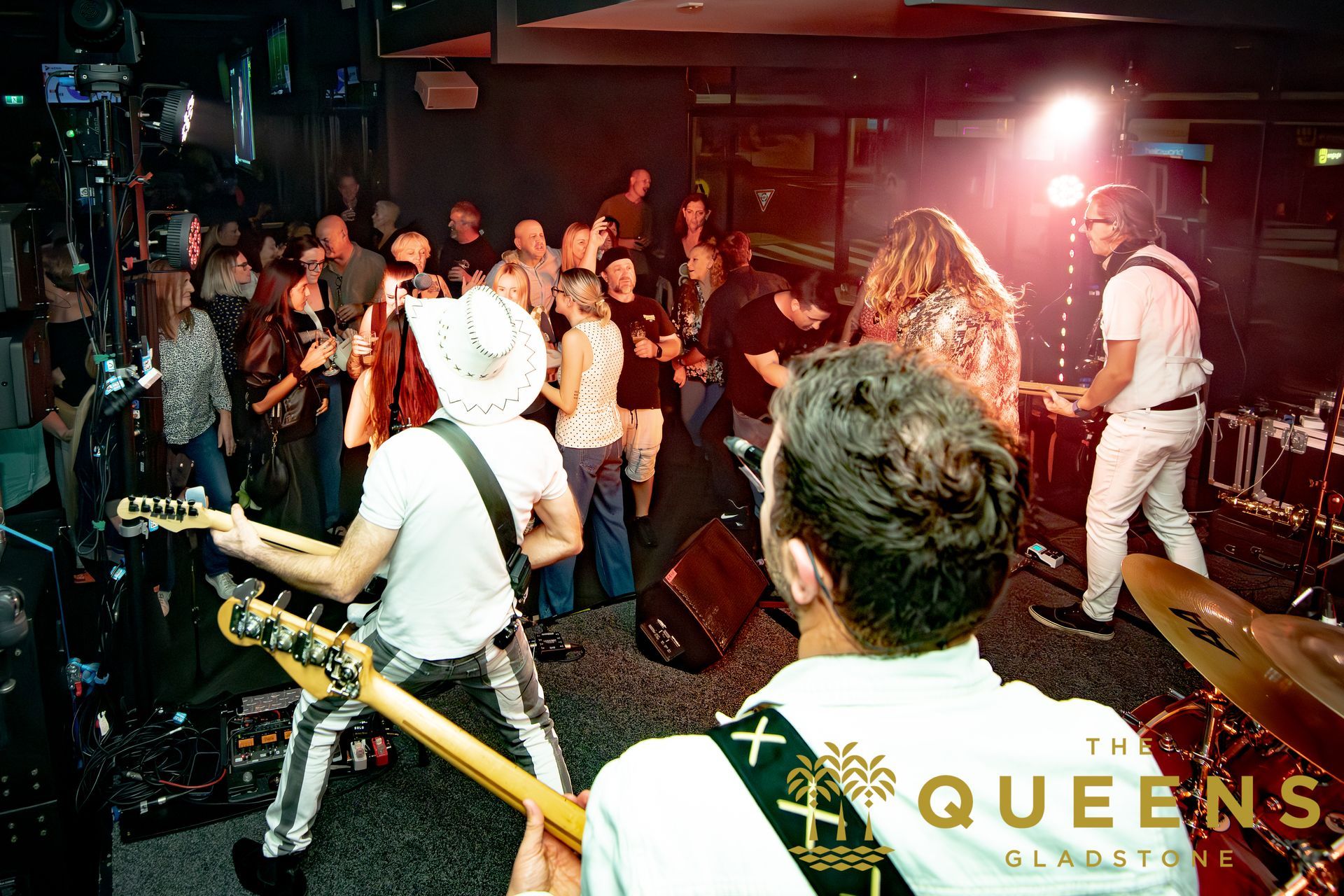Live band performing onstage with a crowd watching in a dimly lit venue