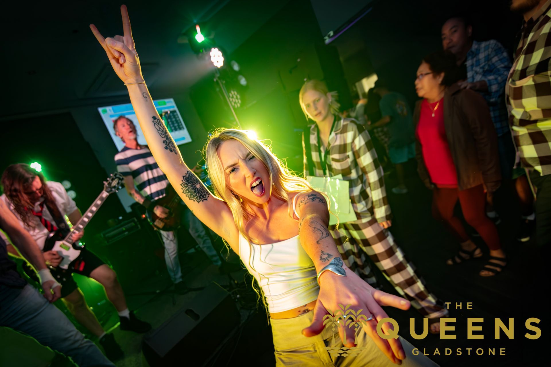 Singer on stage with mic, arm raised, in a green-lit club performance