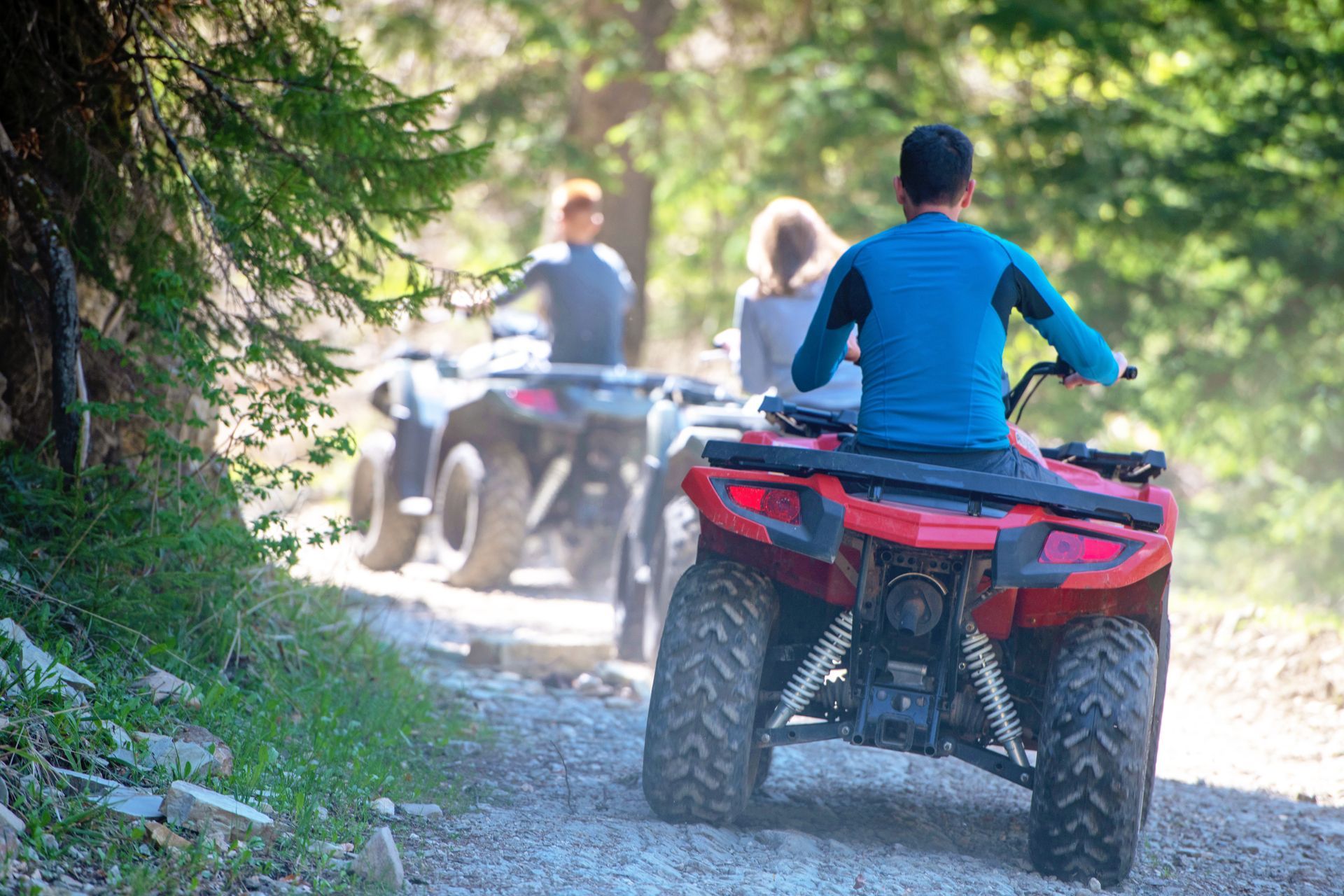 A group of people are riding atvs down a dirt road.