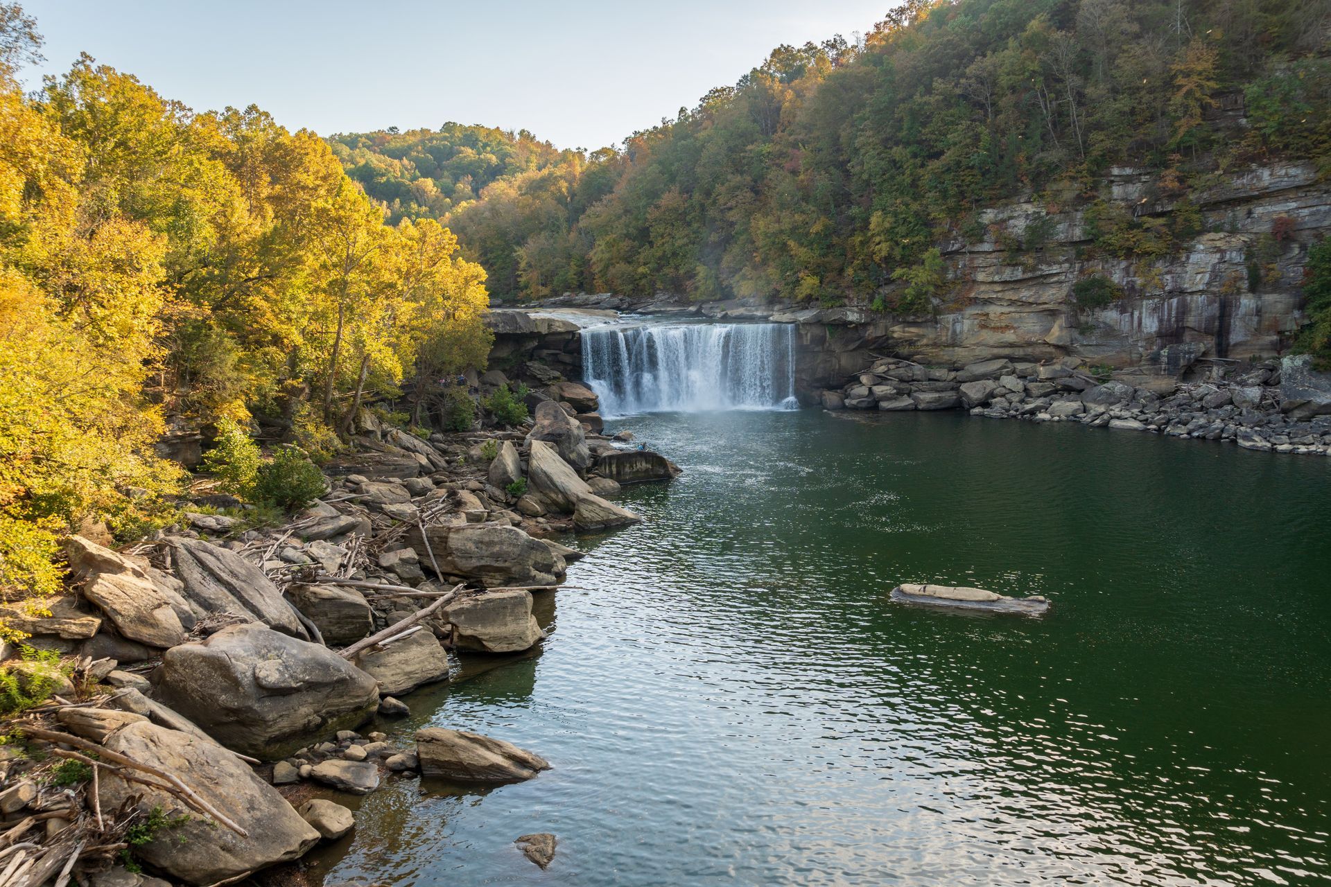 A waterfall is surrounded by trees and rocks in the middle of a river.