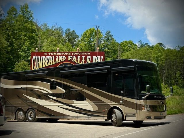 RV parked near a sign for Cumberland Falls, with a brown and black color scheme, sunny day.