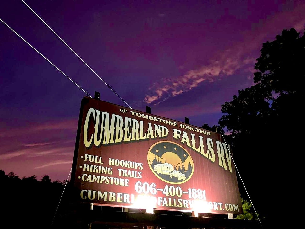 Cumberland Falls RV sign lit at dusk with purple sky and power lines.