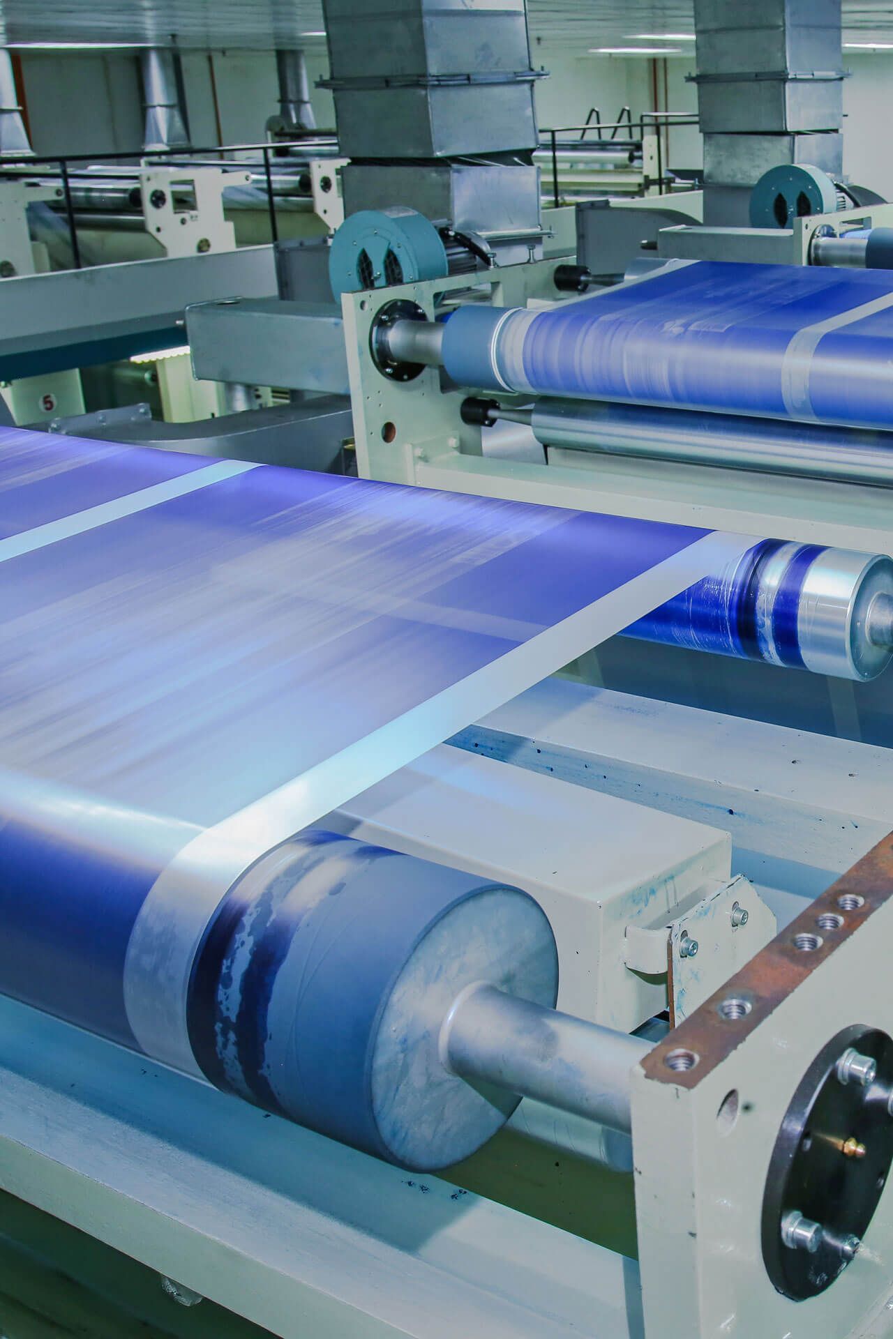 A machine is rolling a blue sheet of paper in a factory.