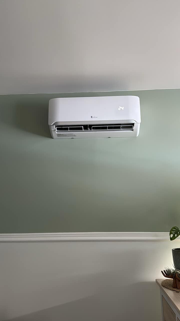 Un climatiseur blanc est accroché sur un mur vert dans une pièce.