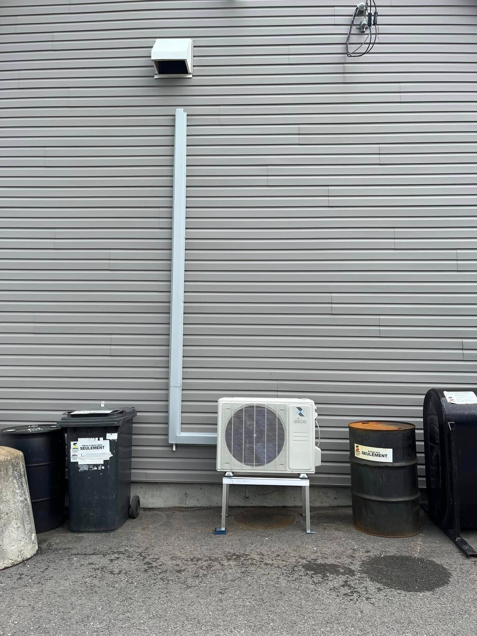 Un climatiseur blanc est fixé sur le côté d'un bâtiment.
