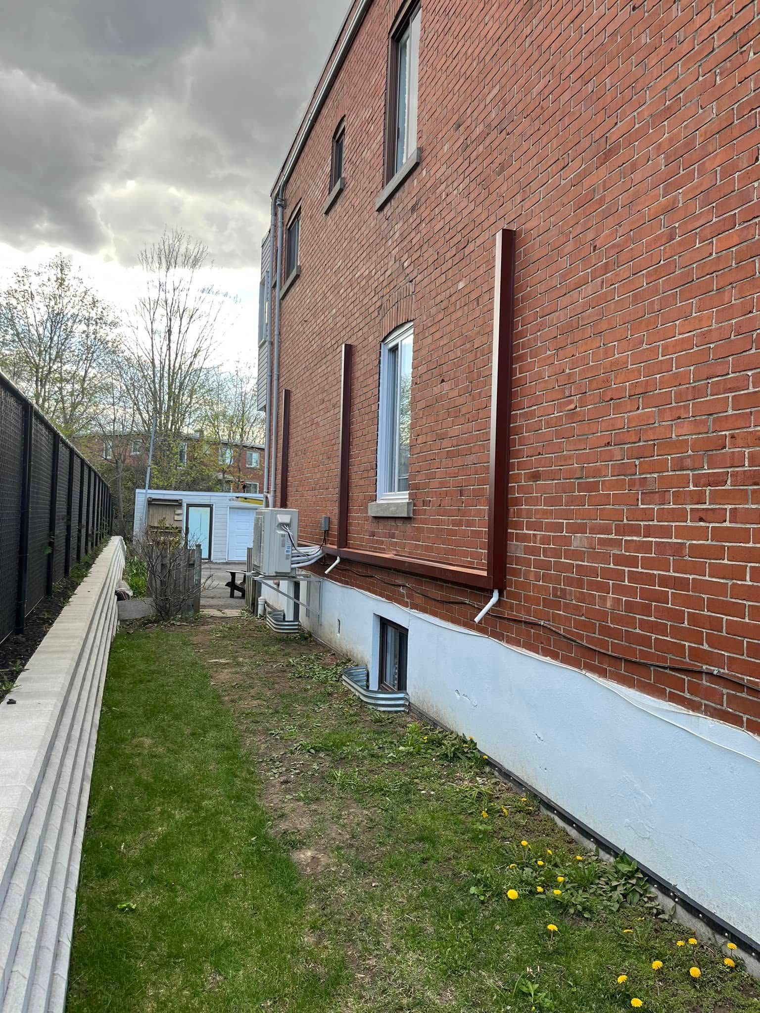 Un bâtiment en briques avec une clôture et de l'herbe devant.