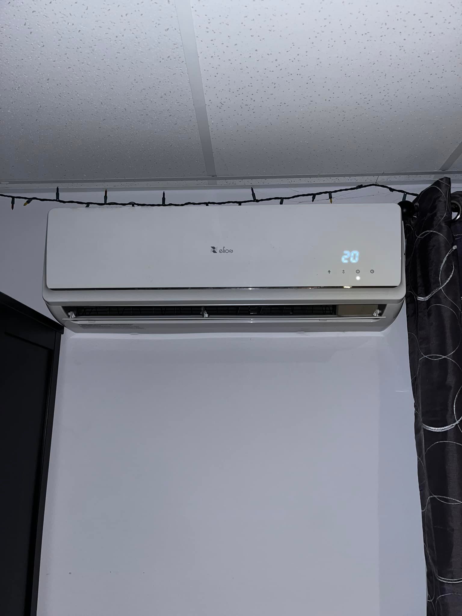 Un climatiseur blanc est accroché sur un mur à côté d'une fenêtre.