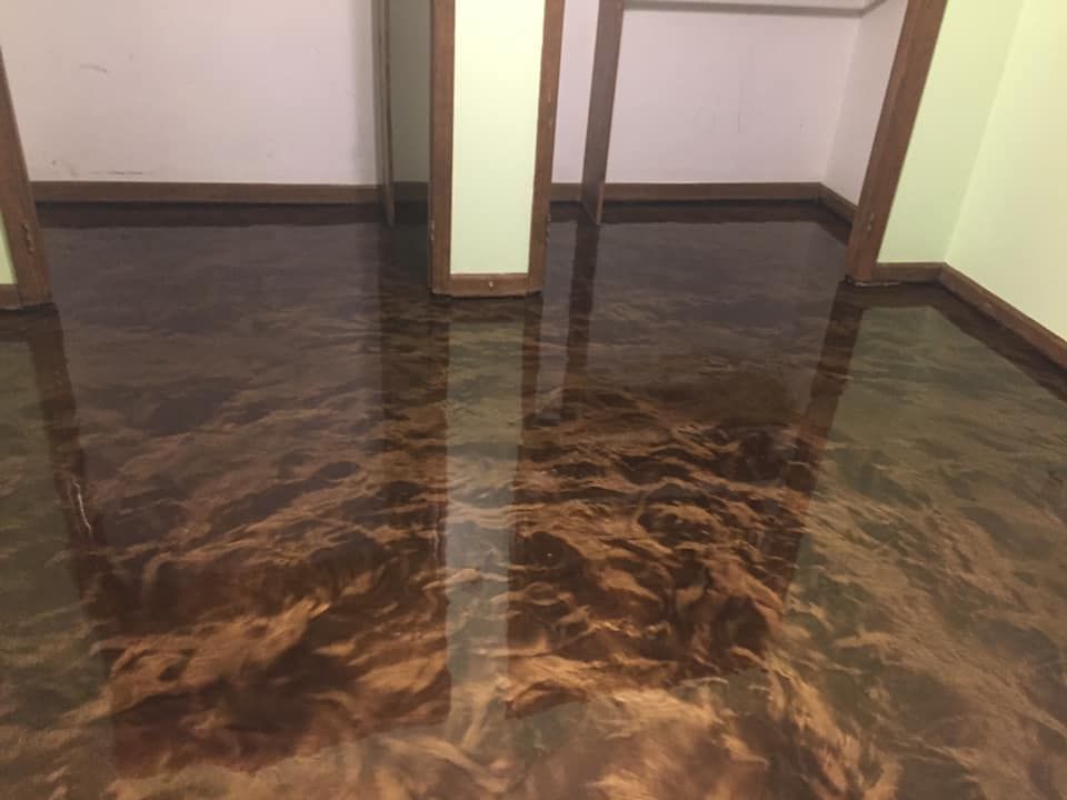 Brown and gold epoxy floor in a room with light green walls and brown trim.