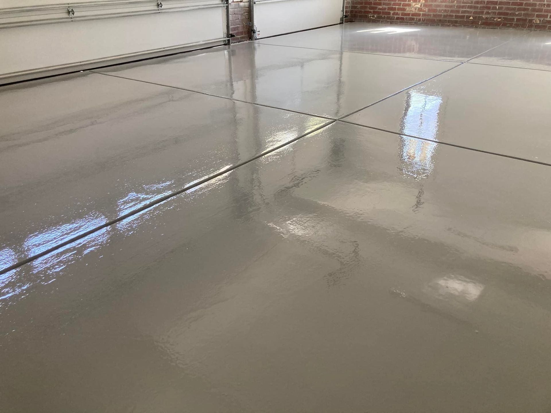 An open garage with a black awning and brick driveway. The garage has white walls and is empty.