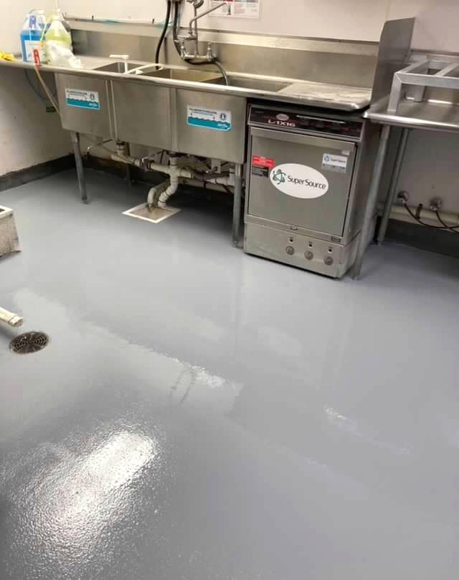 Commercial kitchen with a gray epoxy floor, stainless steel sink, and dishwasher.
