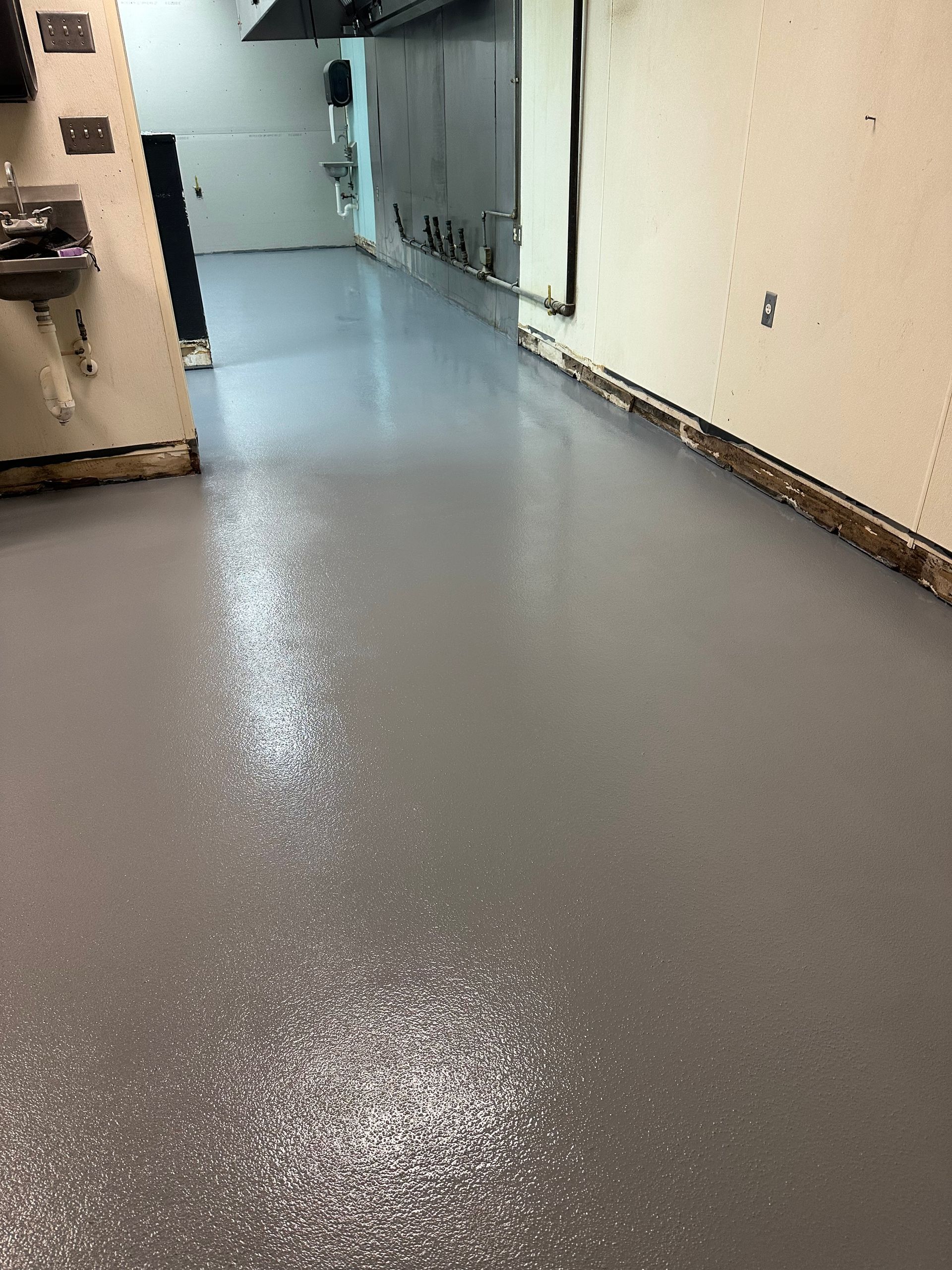 Gray epoxy floor in a commercial kitchen or similar area.