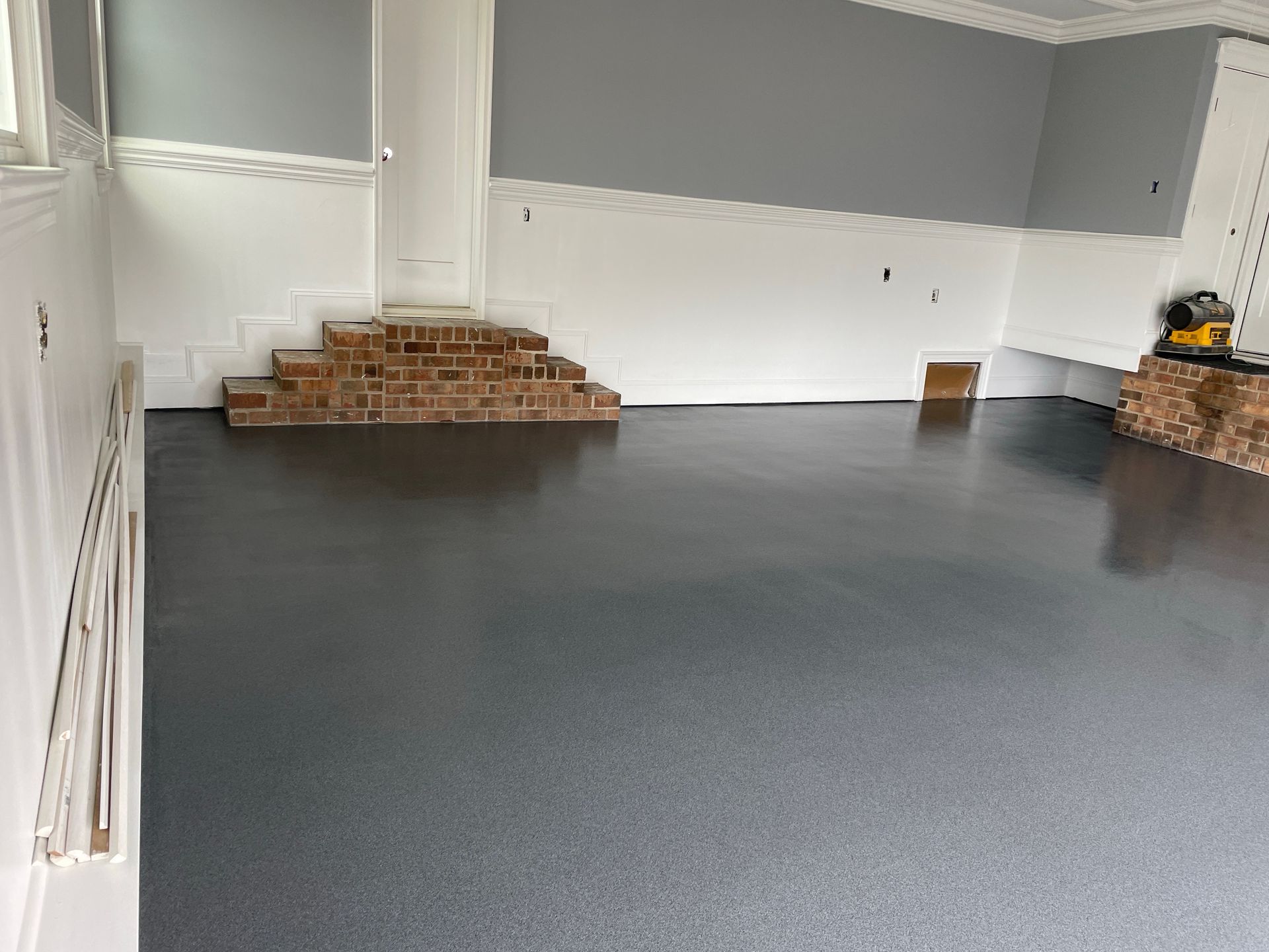 Garage with gray epoxy floor, white walls, and brick accents.