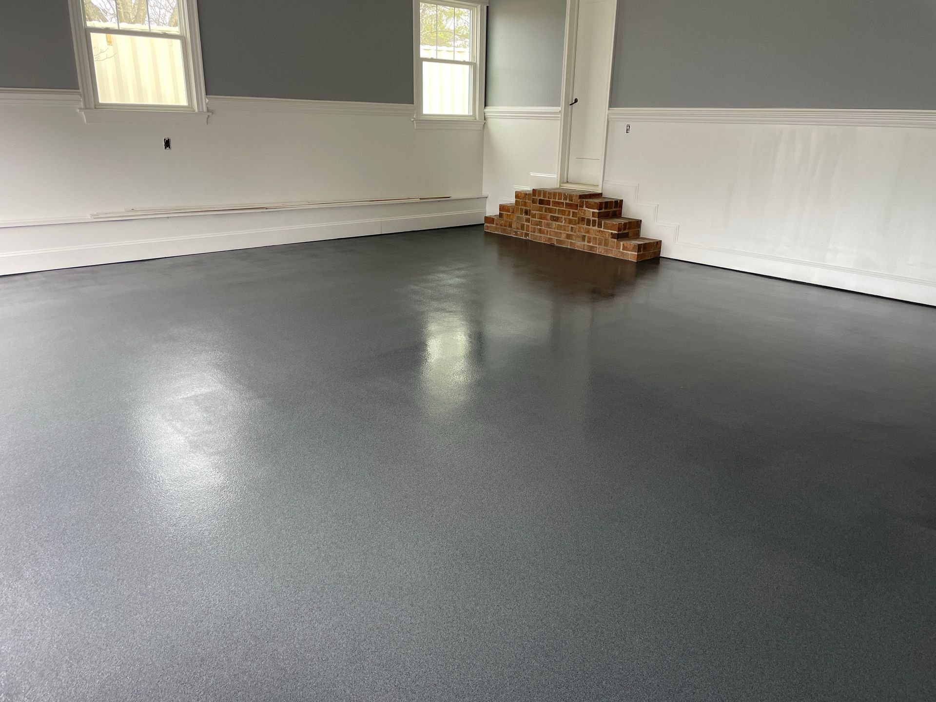 Garage with a glossy, dark gray epoxy floor and white walls.