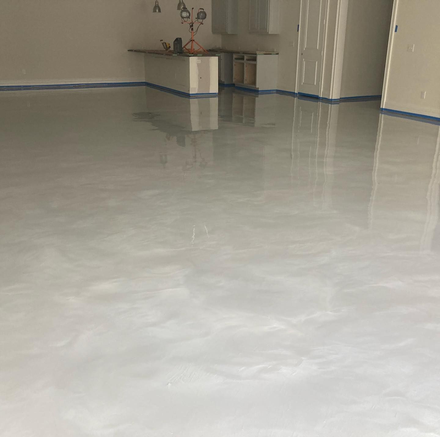 Shiny gray epoxy garage floor with swirl patterns, reflecting light.