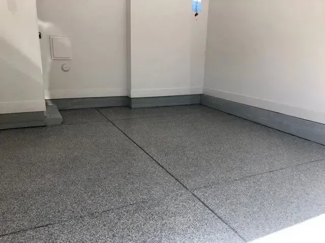 Gray speckled epoxy garage floor and trim, white walls.