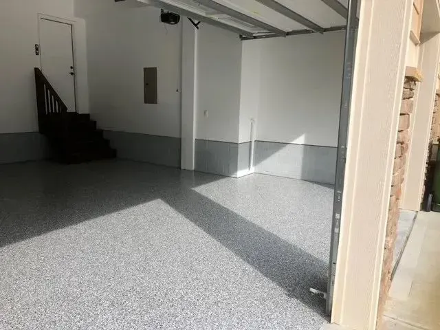 Interior of a garage with a gray speckled floor and white walls.