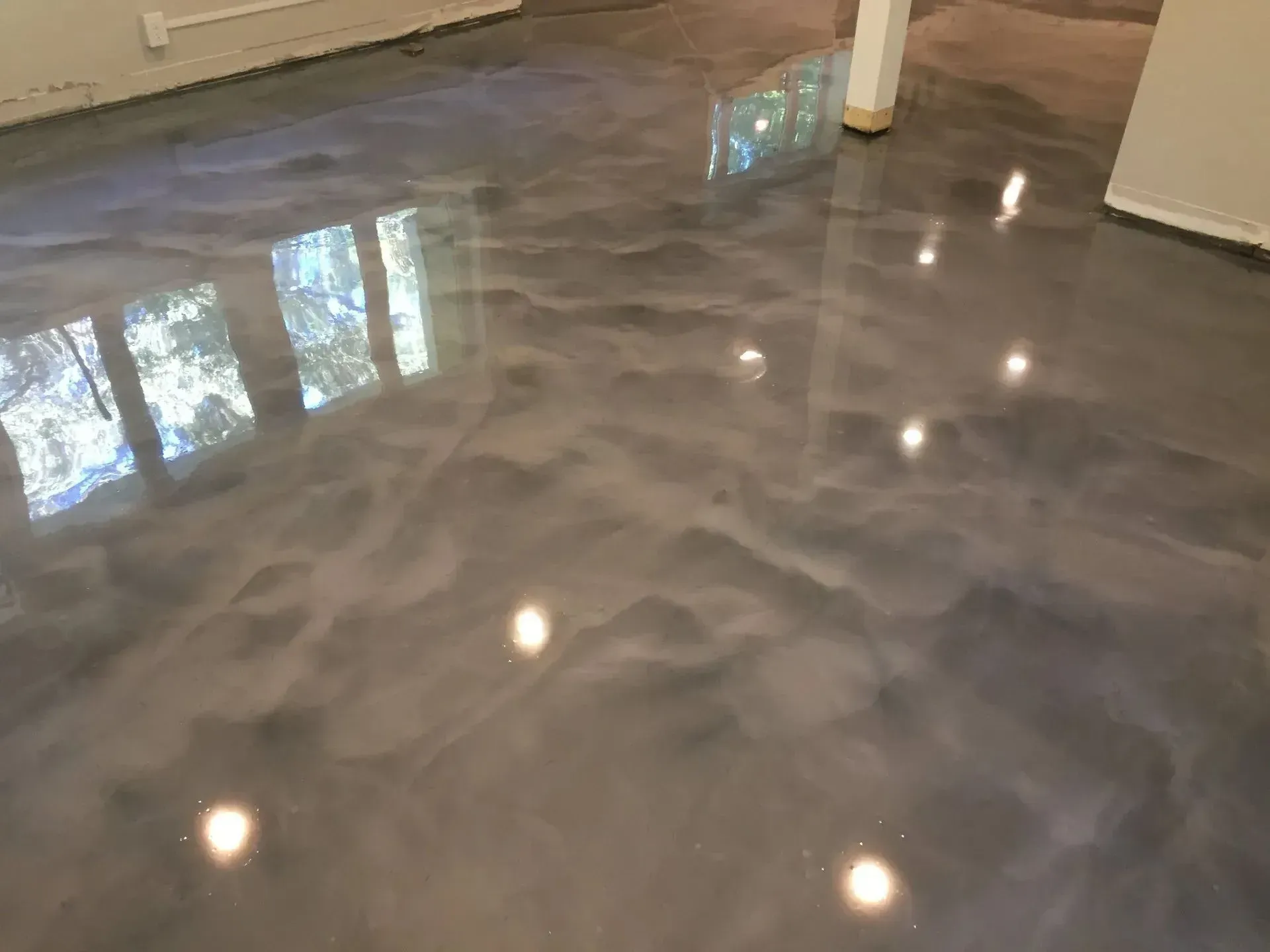 Metallic epoxy floor with swirled silver and gray hues reflecting ambient light.