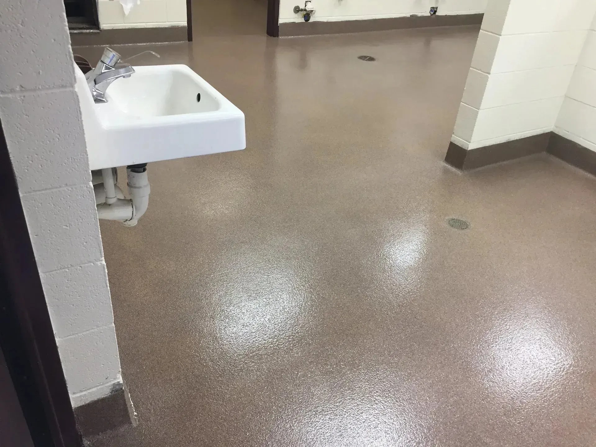 Bathroom with a white sink, brown speckled floor, and off-white walls.