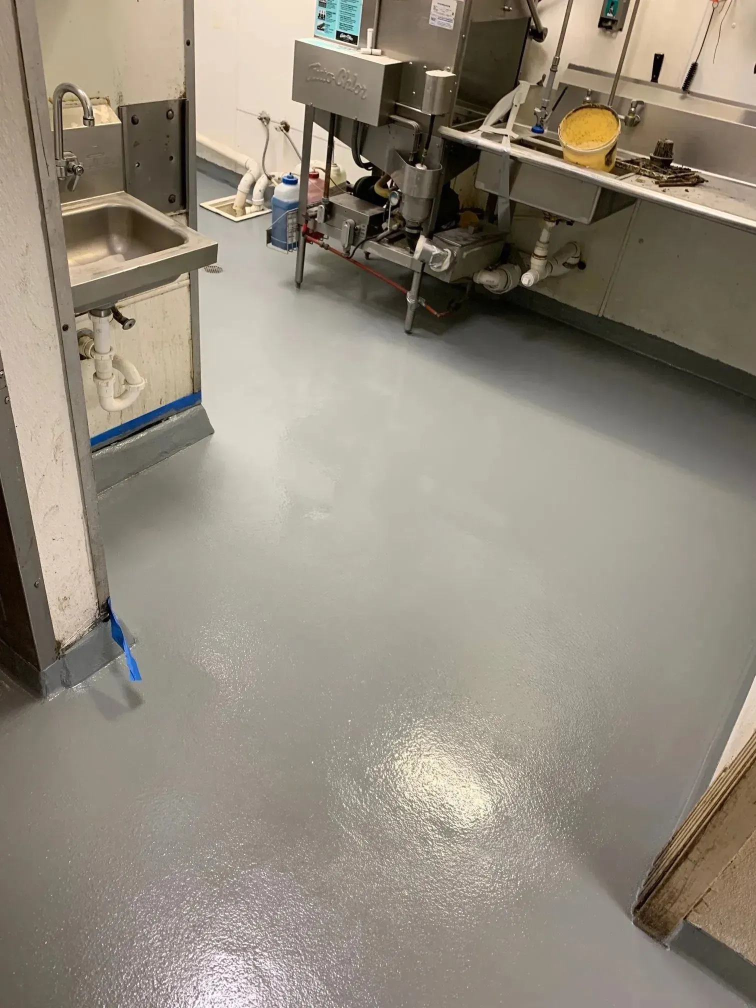 Gray industrial kitchen floor with spilled white substance. 
