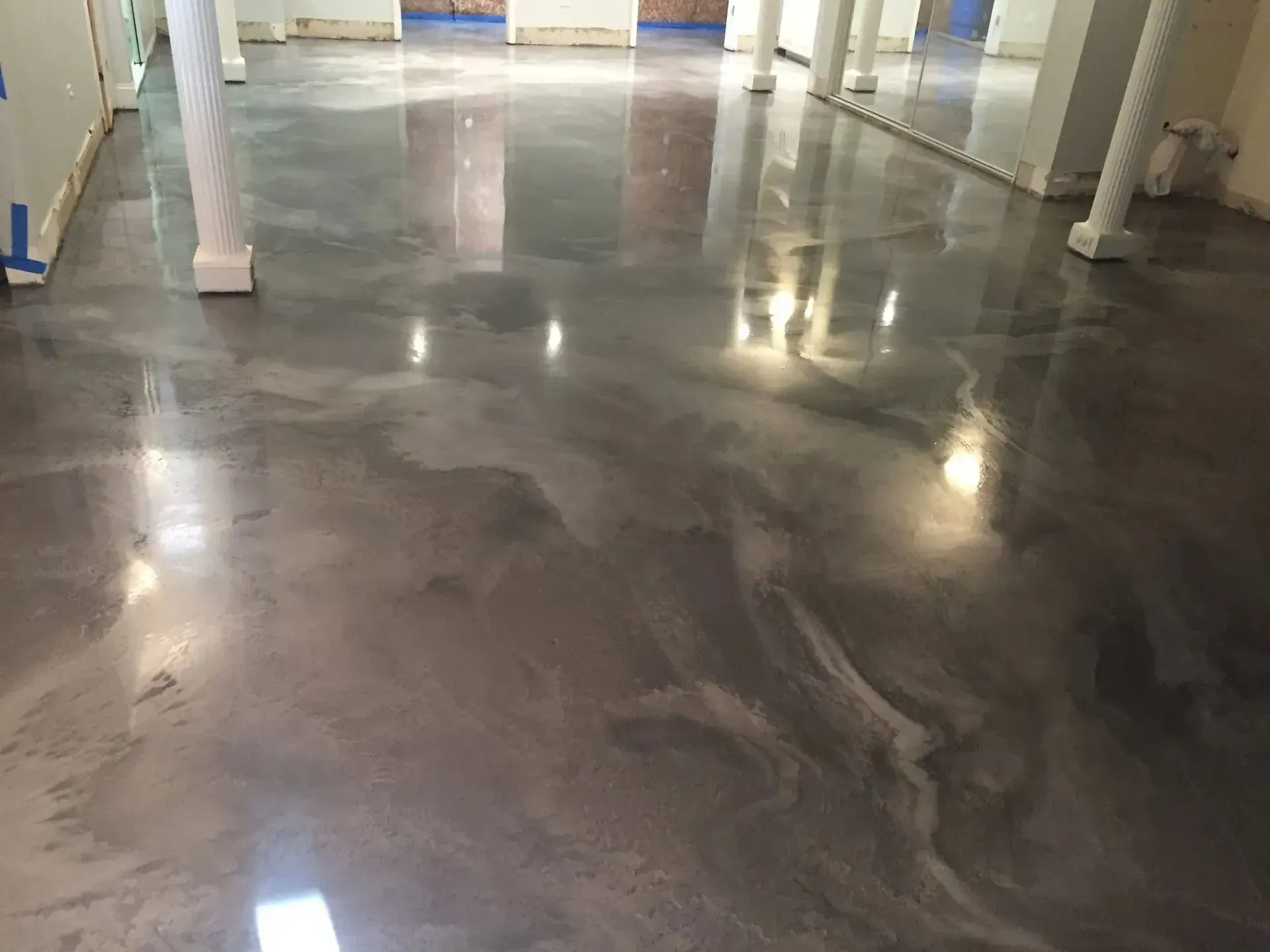 Metallic epoxy flooring, gray and silver swirls, reflecting light in a large room.