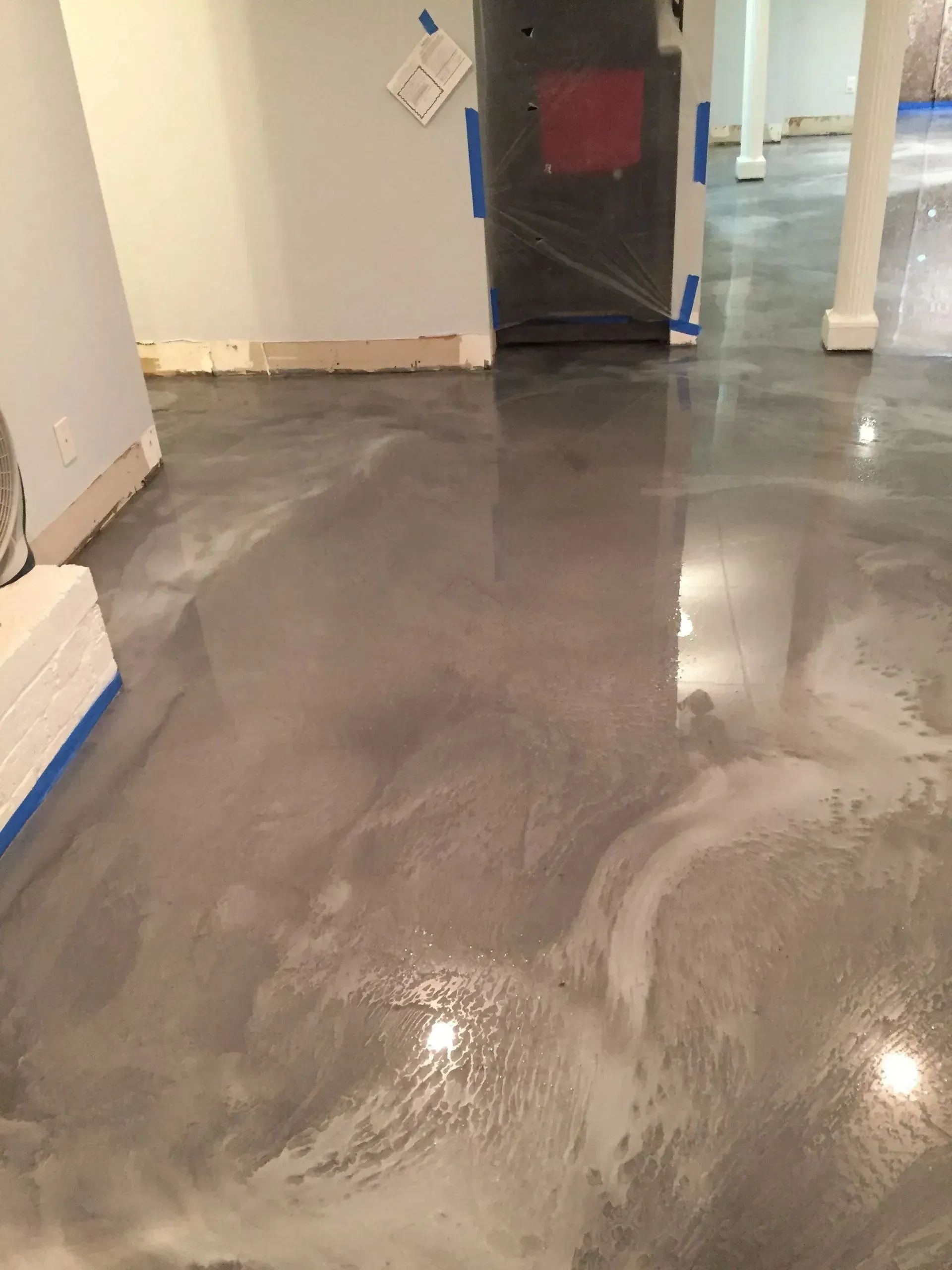 Shiny gray epoxy floor in a room under construction, reflective surface.