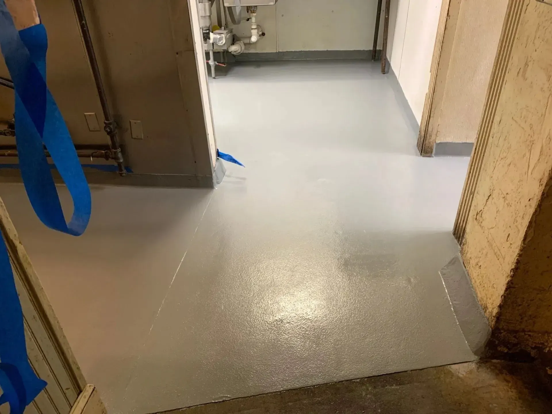 Light grey painted floor in a commercial setting, visible doorway, blue strap hanging down.