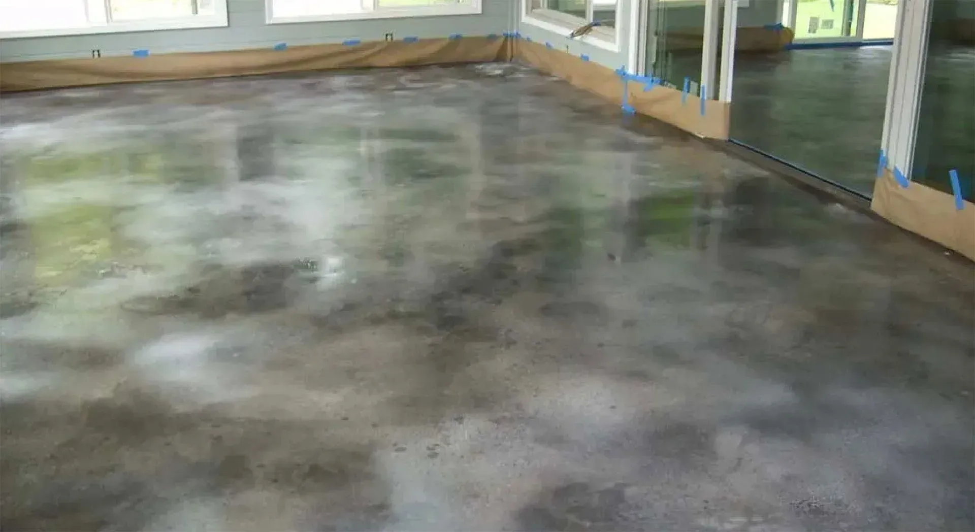 Polished concrete floor in a room, reflecting light with shades of gray and white.