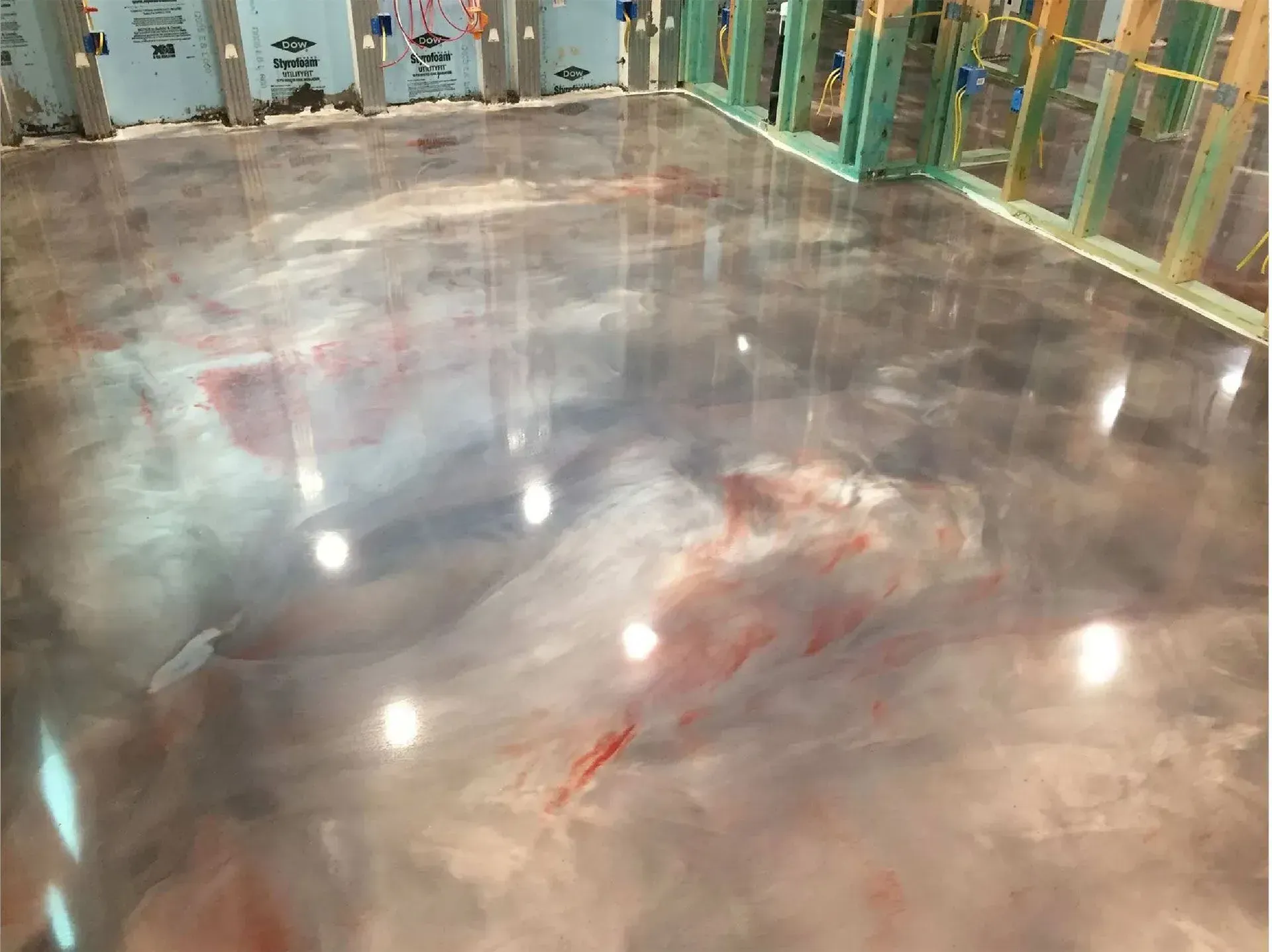 Metallic epoxy flooring with swirling silver, gray, and red pigments. Interior of a room under construction.