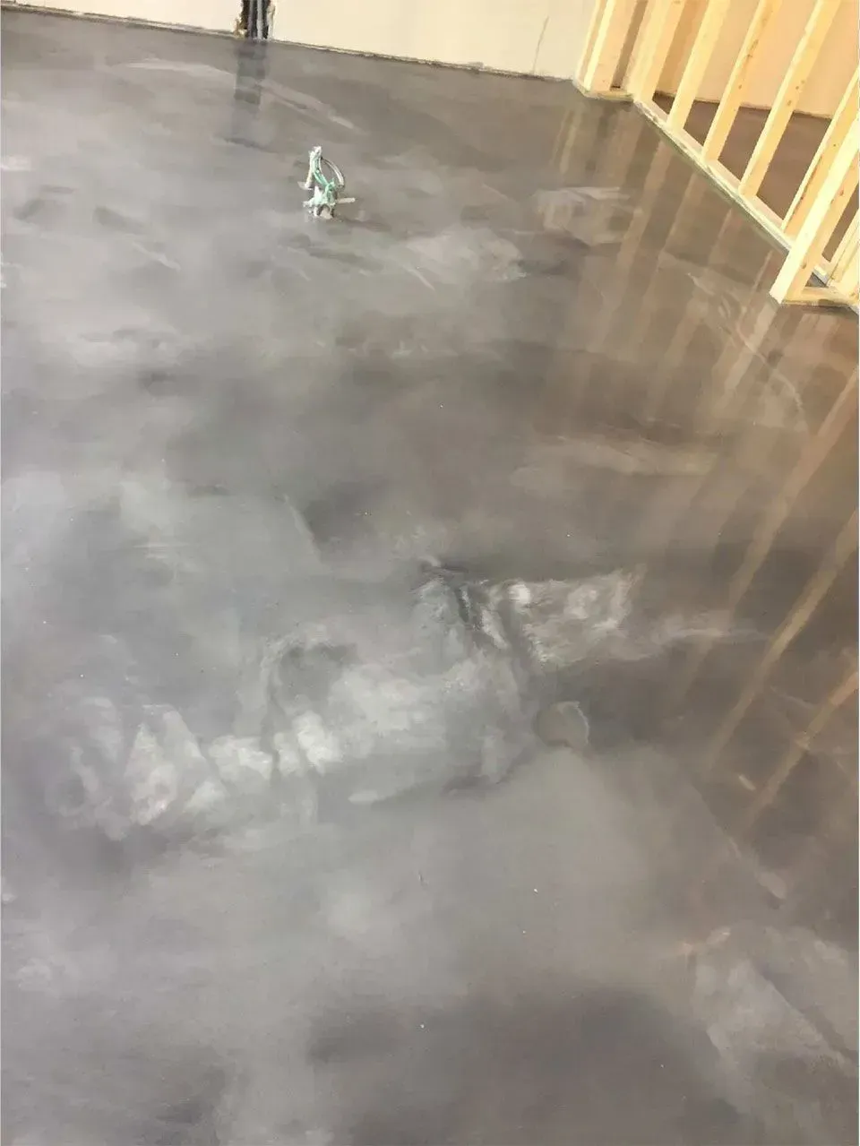 Gray metallic epoxy floor with light reflections; wooden framing on right.