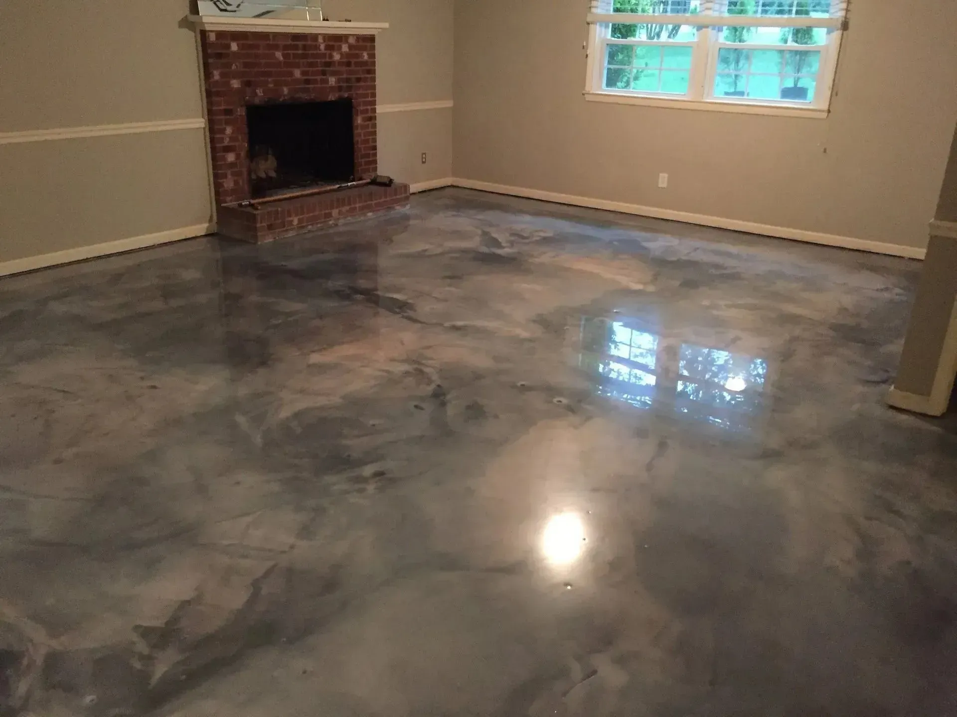 Metallic epoxy floor in a room with a brick fireplace and a window.