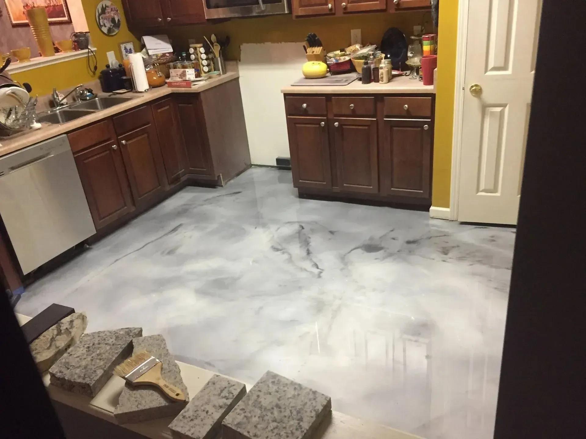 Kitchen with white-painted floor, brown cabinets, white appliances, and granite samples on a ledge.
