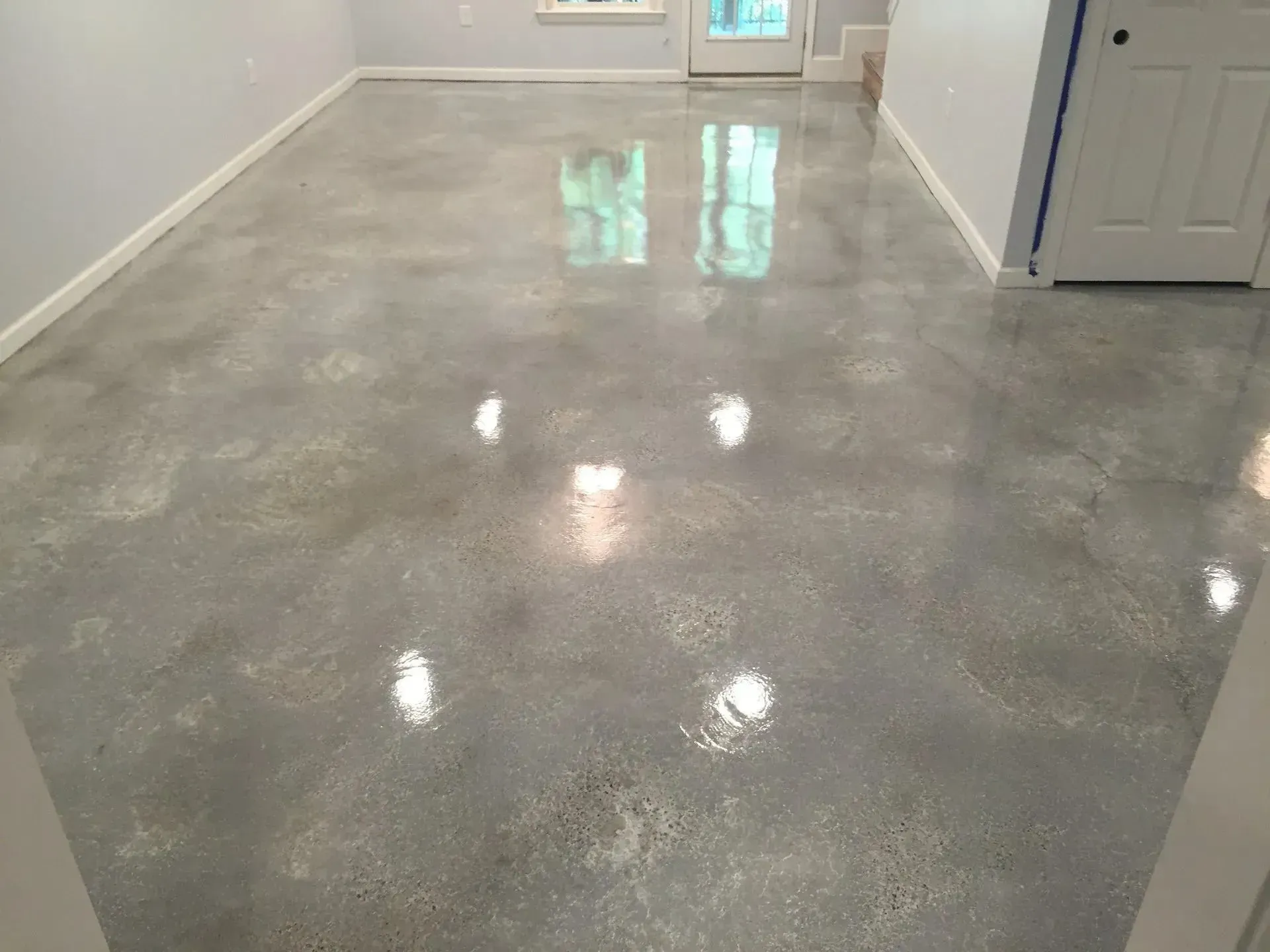 Polished concrete floor in a room, reflecting light with gray tones.