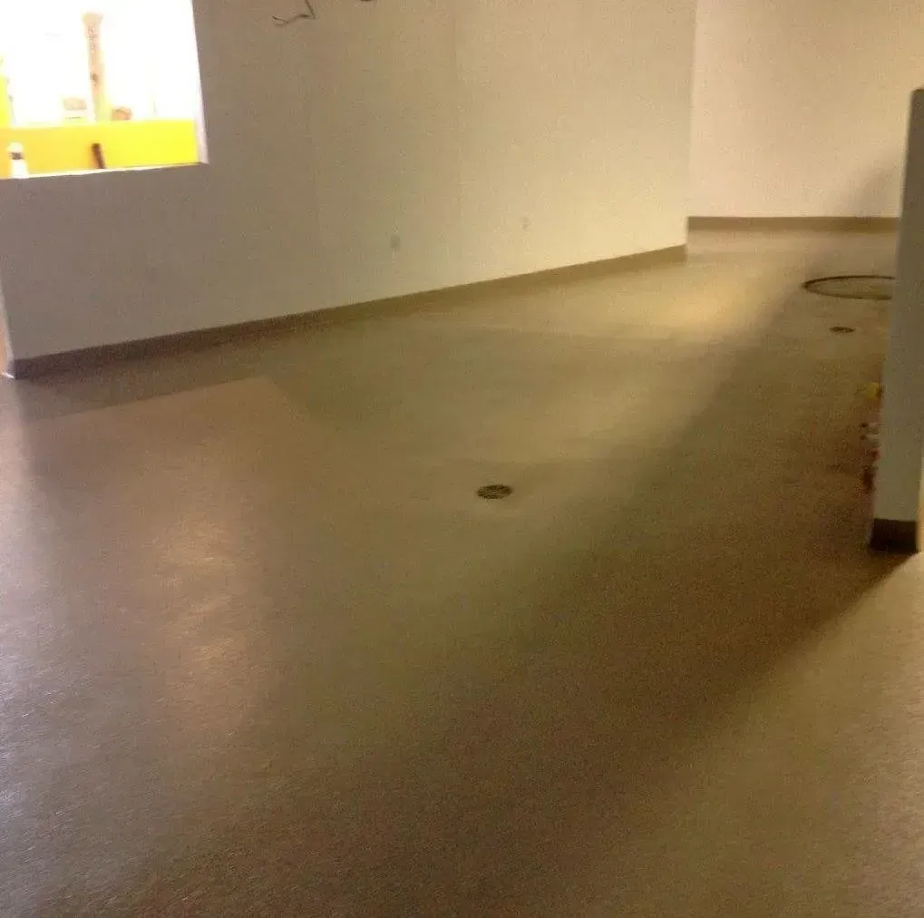 Empty room with light brown polished concrete floor and white walls.