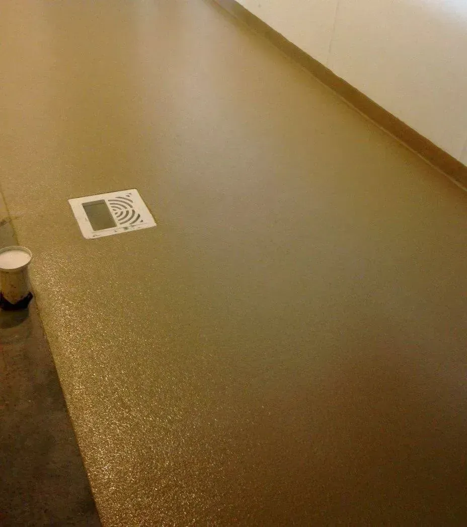 Brown epoxy-coated floor, light reflecting, with a drain cover and a paint can.
