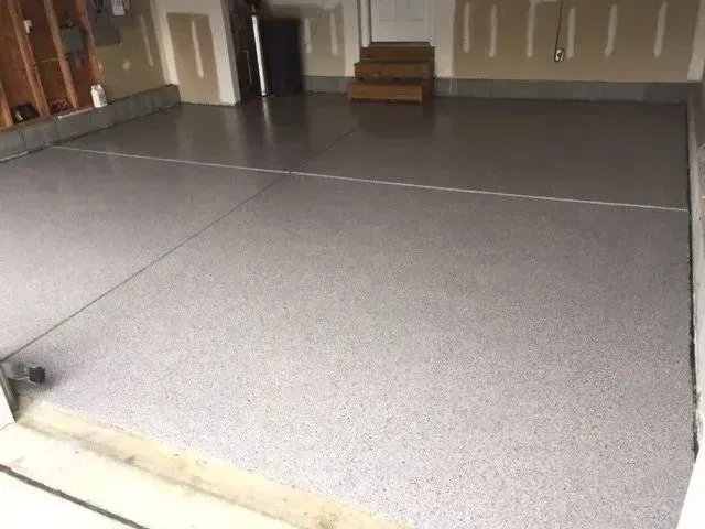 Garage floor with light gray speckled epoxy coating.