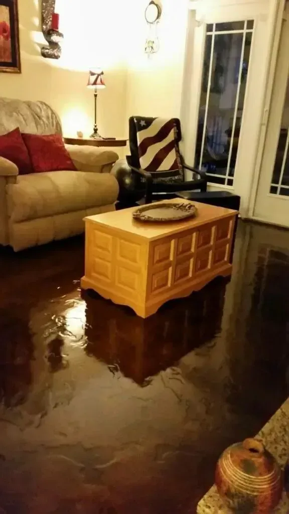 Living room with water on floor, sofa, coffee table, and door.