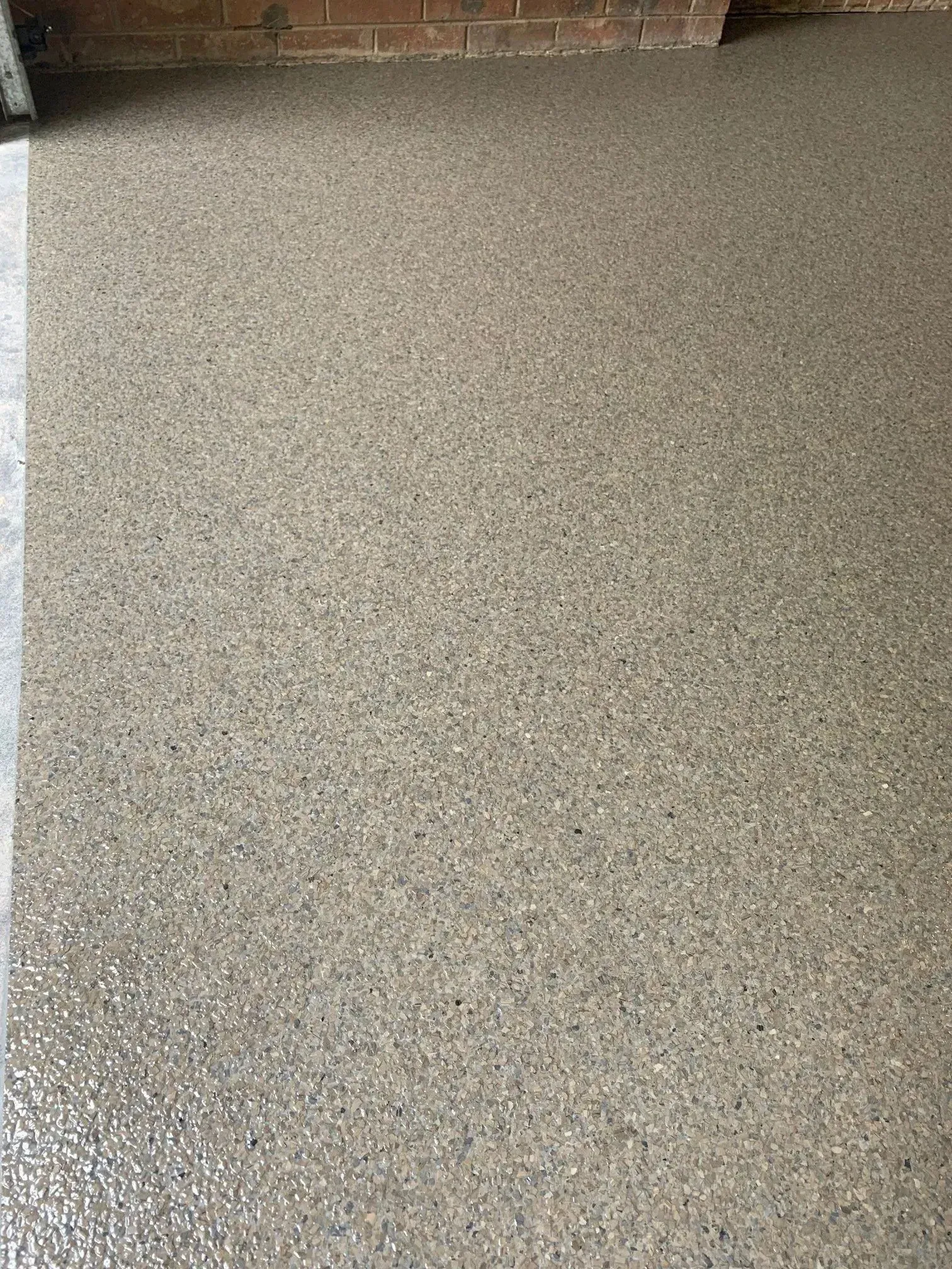 Speckled, beige floor with a brick wall in the background.