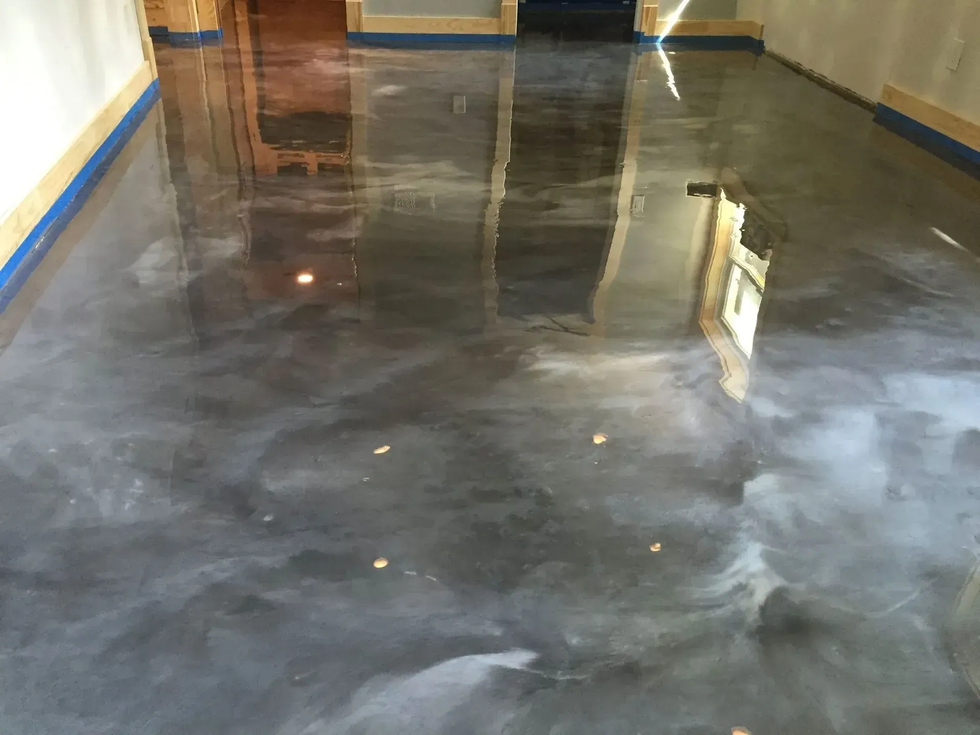 Shiny, metallic gray epoxy floor in a room, reflecting light.