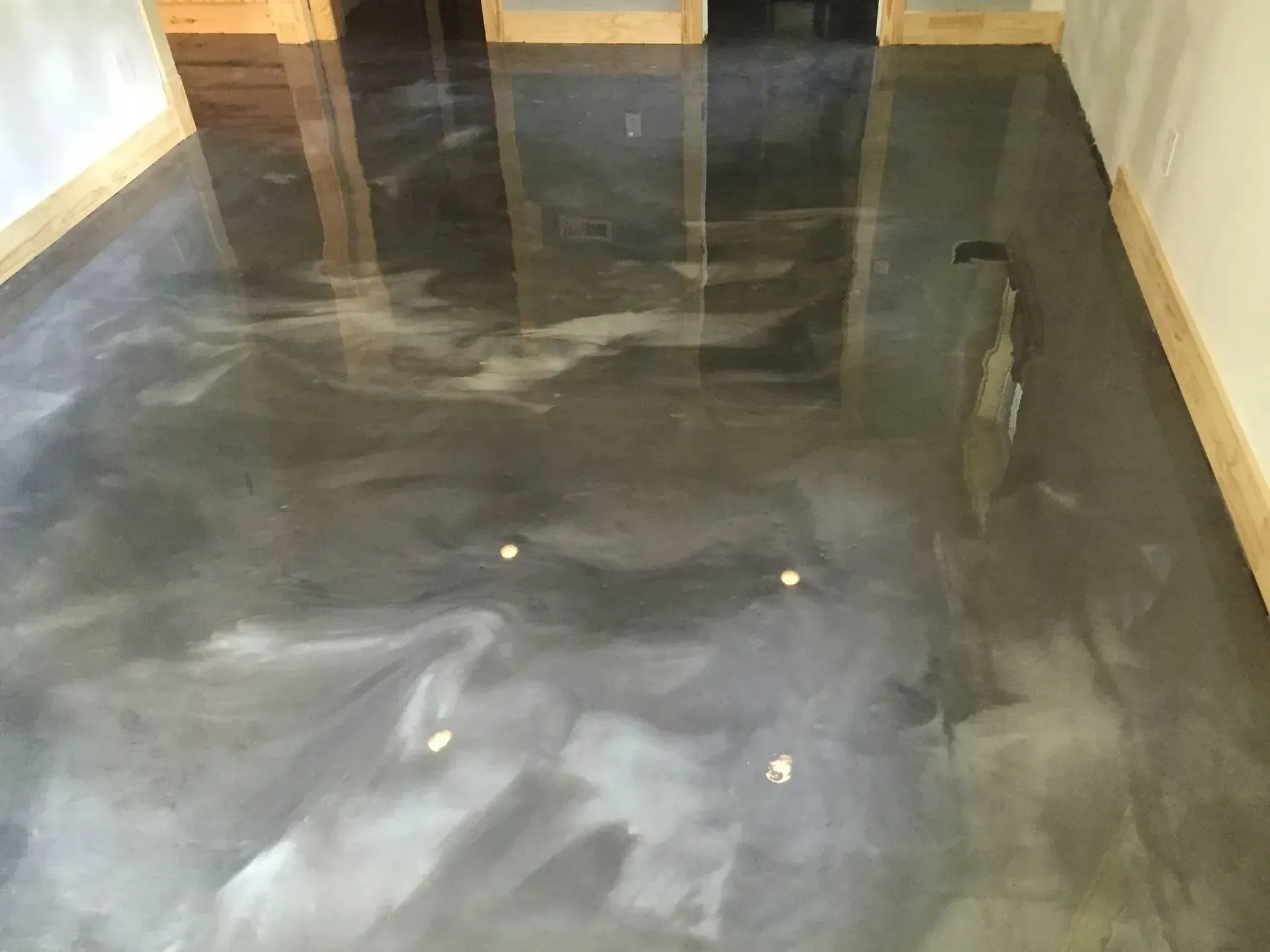 Metallic epoxy floor, gray and white swirling design, reflecting light in a room.