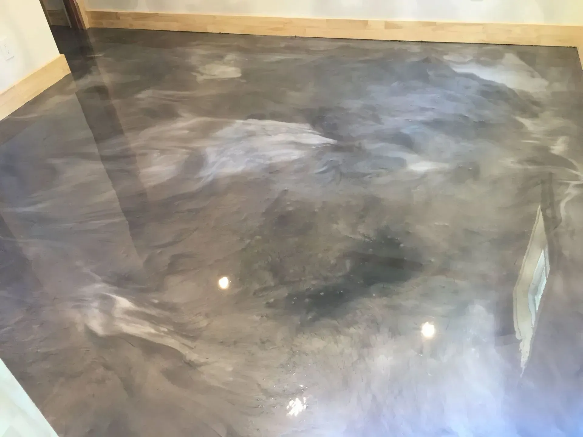 Metallic, epoxy floor with swirling shades of gray and white. Reflective surface.