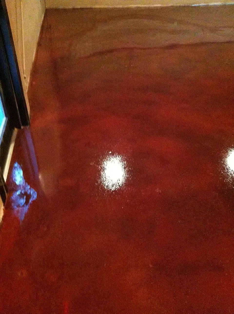 Glossy, reddish-brown concrete floor with bright light reflections.