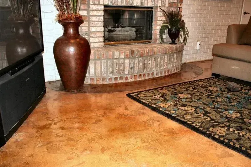 Living room with stained orange concrete floor, fireplace, and patterned rug.