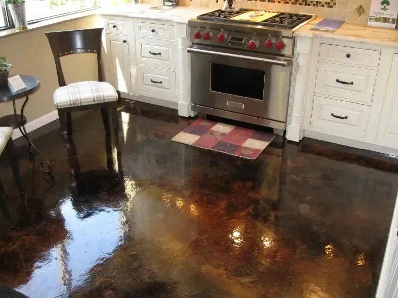 Kitchen with glossy brown stained concrete floor, white cabinets, and stainless steel oven.