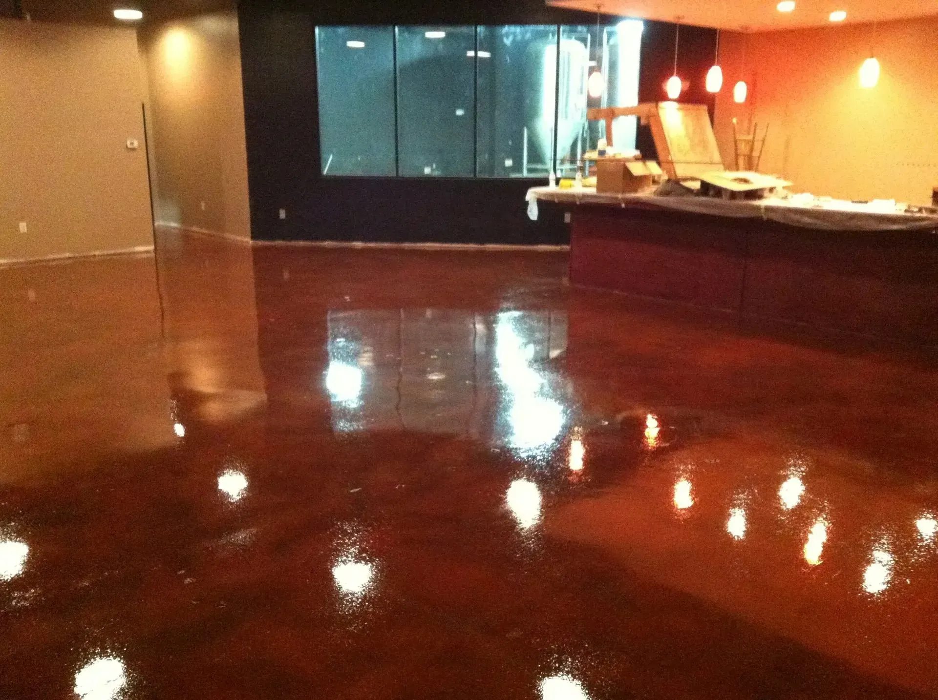 Shiny, reddish-brown concrete floor reflecting bright lights in a commercial interior.