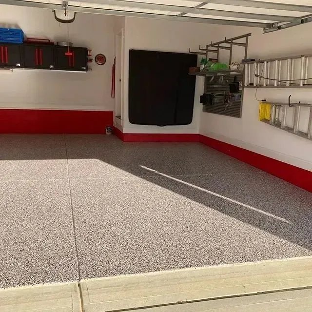 Clean garage with speckled gray floor and red trim; shelves, cabinets, and ladder against white walls.