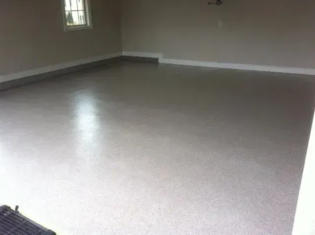 A garage with a gray, epoxy-coated floor, painted walls, and a small window.