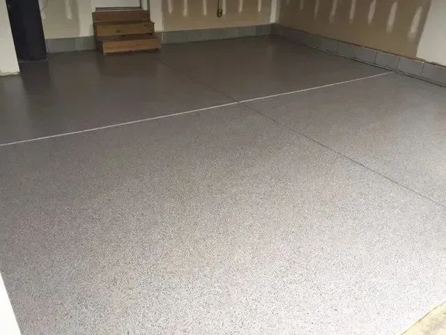 Gray epoxy-coated garage floor with flecks. A door and stairs are visible in the background.