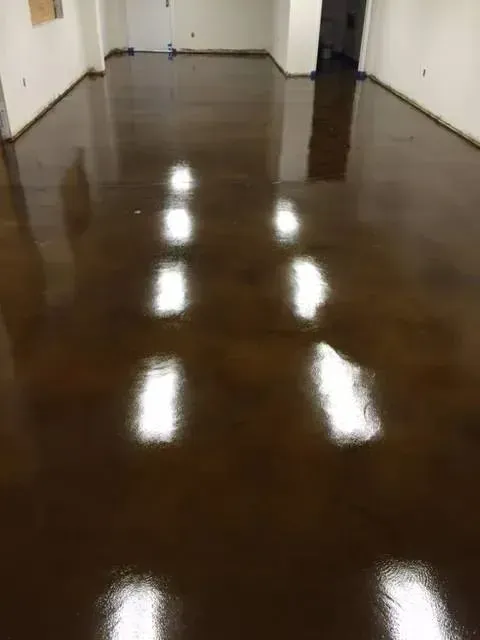 Brown, glossy epoxy floor in a room, reflecting overhead lights.