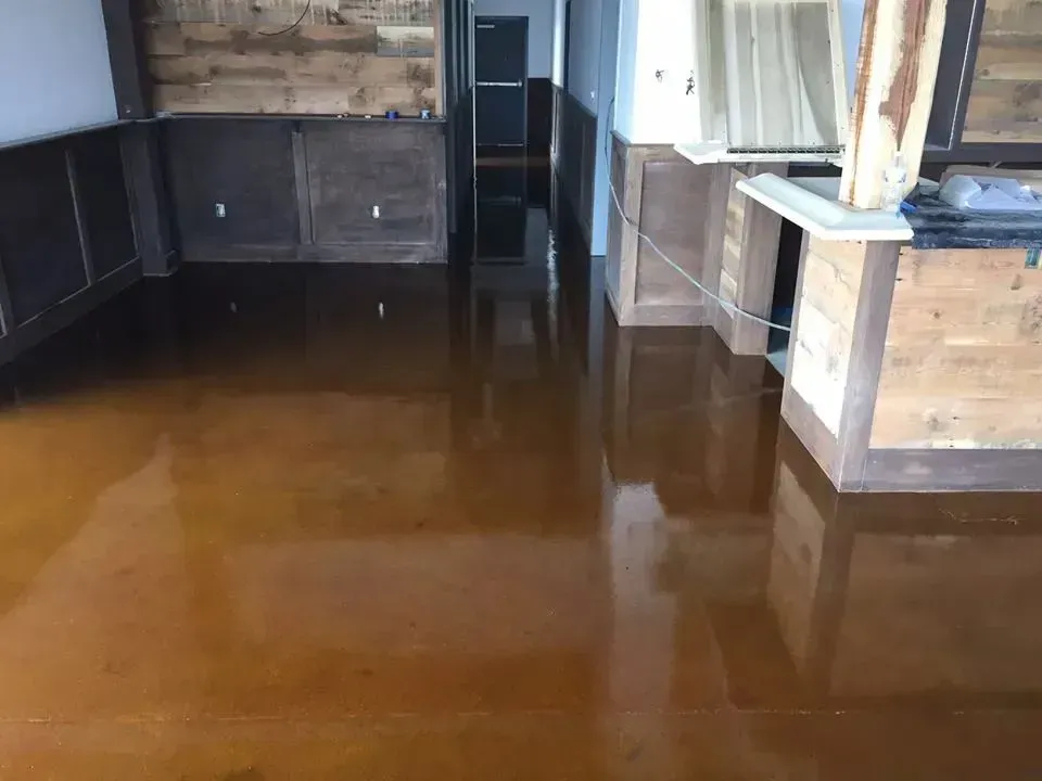 Brown, glossy floor in a room with wood paneling. The floor reflects the room's details.