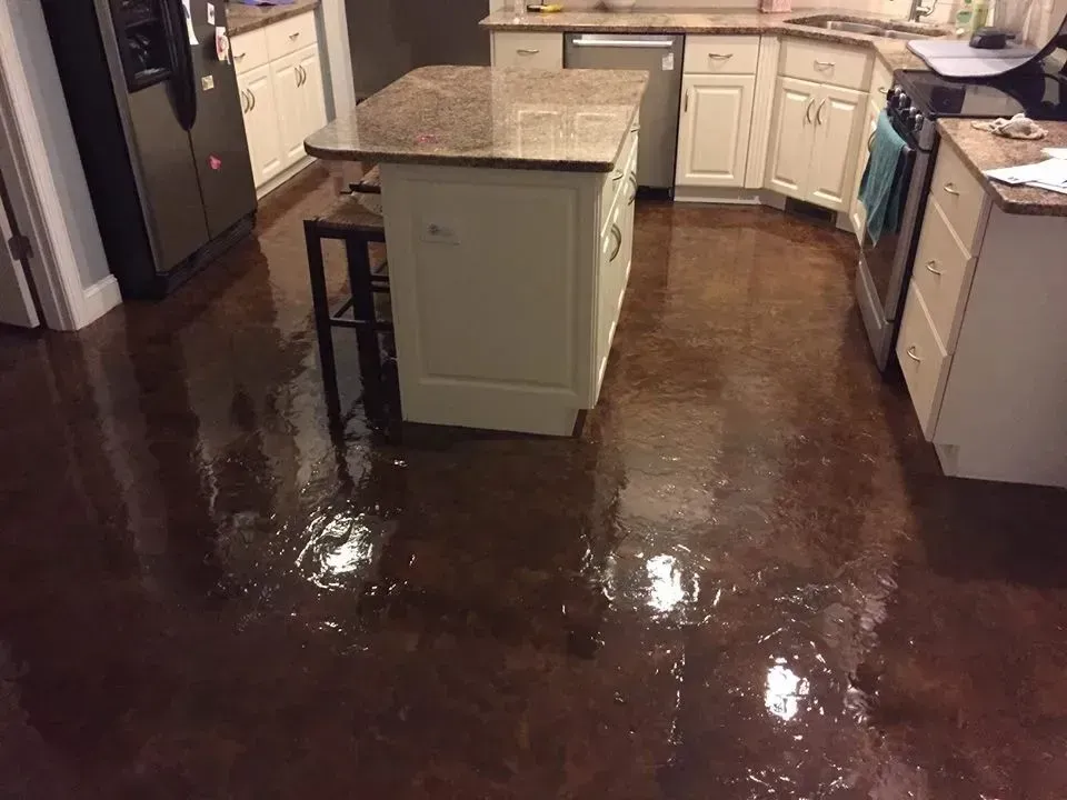 Kitchen with brown stained concrete floor, white cabinets, and granite countertop island.